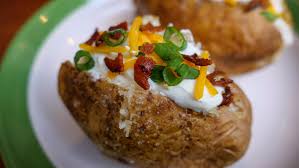 Baked potato with sour cream , cheese , bacon and green onions at smokehouse bbq restaurant