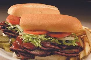 Smoked brisket sandwich with lettuce, tomato, and fries at Kansas City smokehouse barbecue restaurant