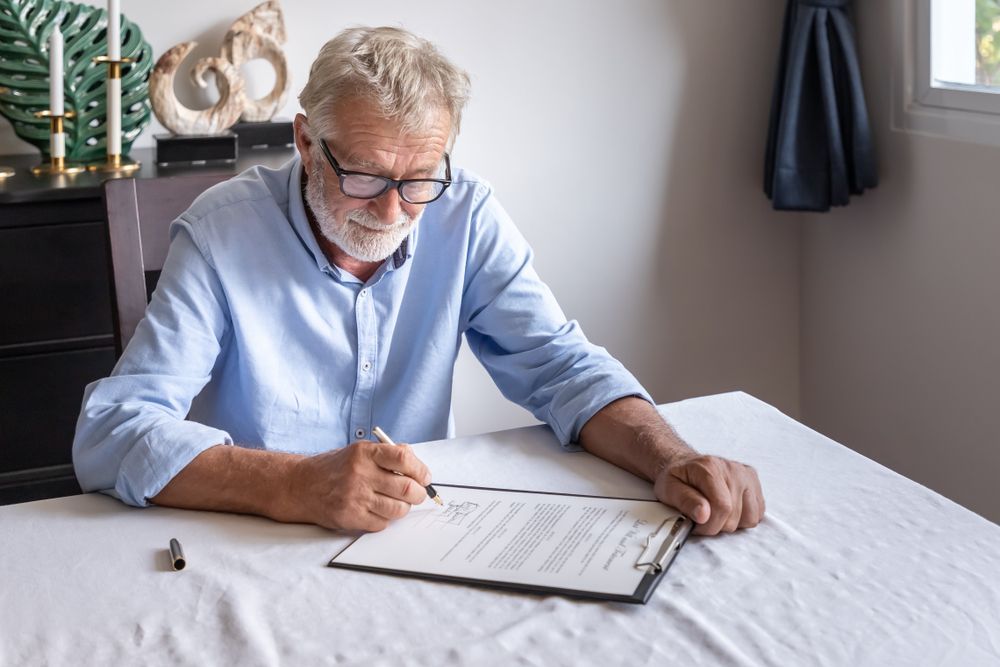 Man signing document on clipboard at table.