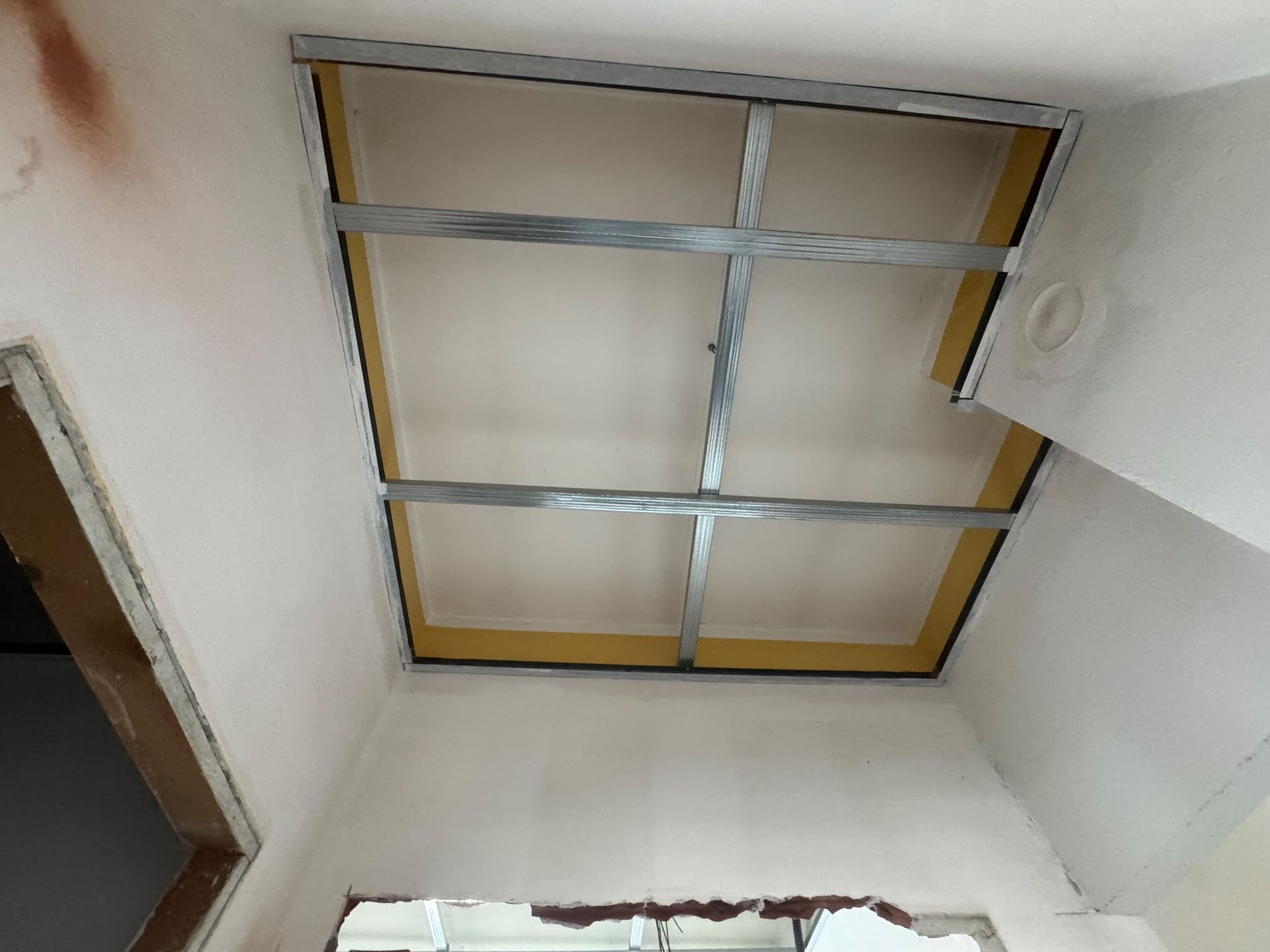 Soffitto con struttura metallica a vista e pannelli isolanti gialli in una stanza non finita