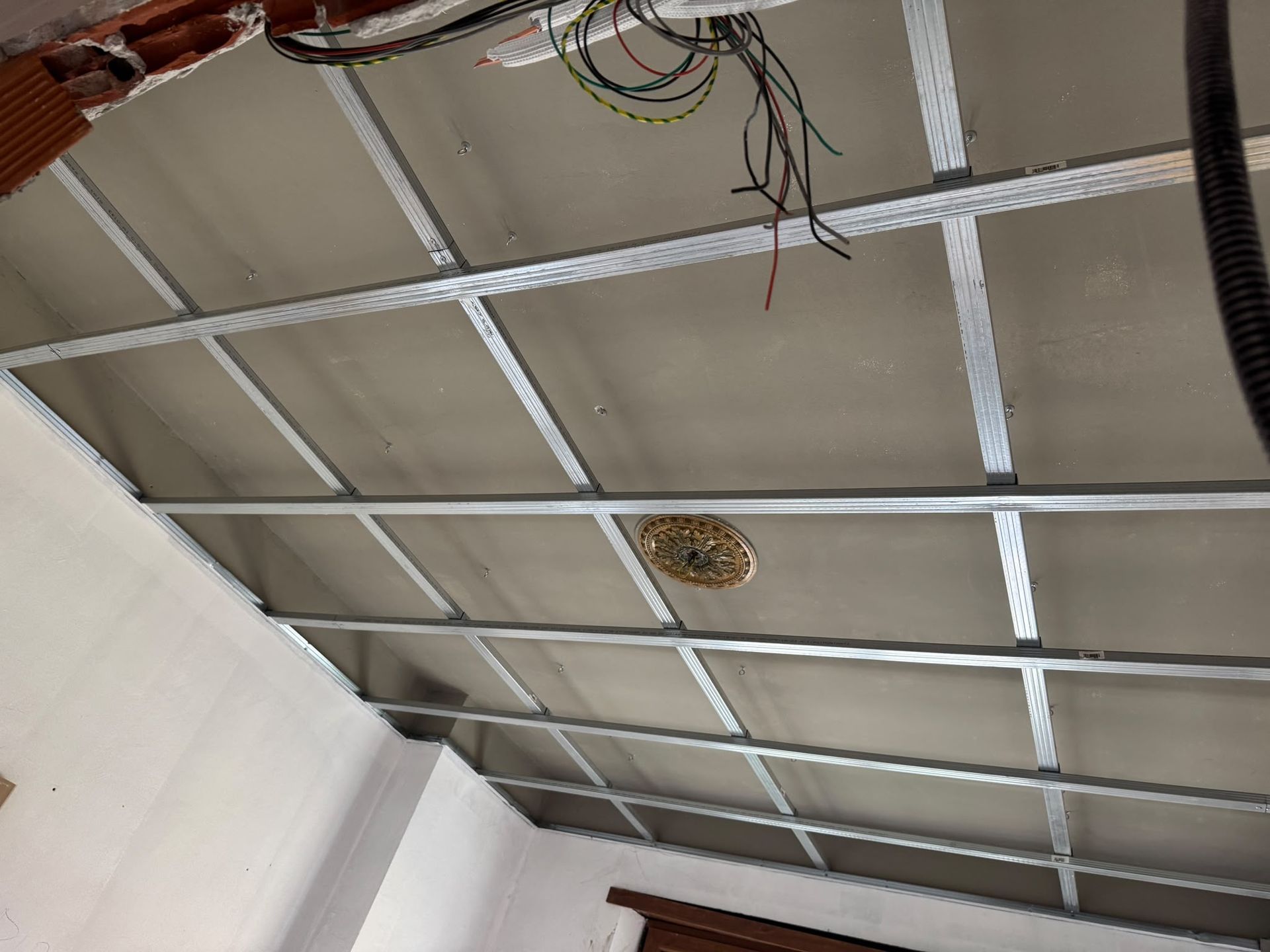 Soffitto in costruzione con struttura metallica, cablaggio e aperture circolari per le bocchette di ventilazione