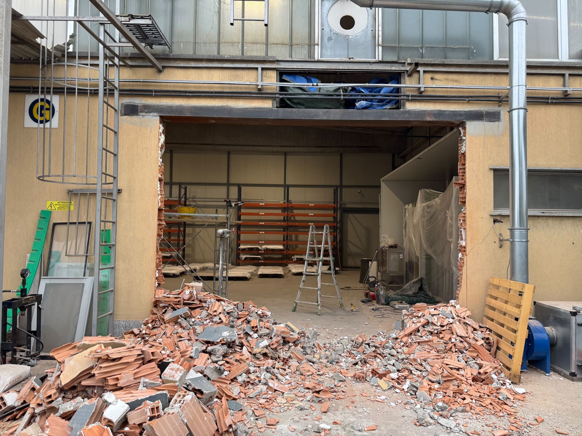 Interno di un edificio parzialmente demolito, con macerie, scale e strutture metalliche a vista
