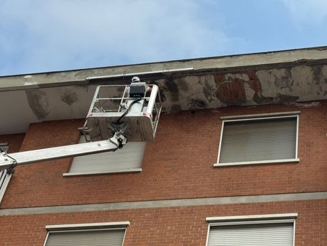 Vigile del fuoco su una piattaforma aerea al lavoro accanto al tetto di un edificio in mattoni