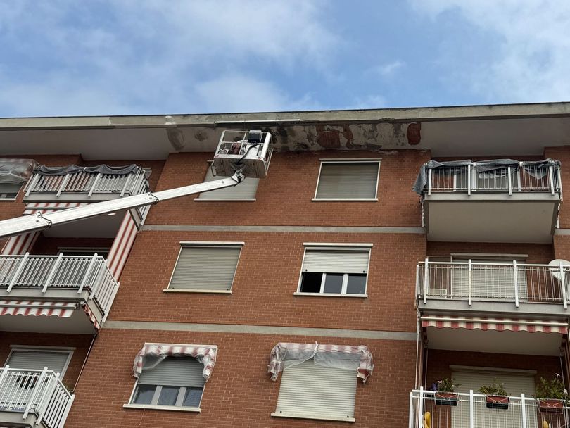 Condominio in mattoni con balconi e finestre aperte sotto un cielo azzurro
