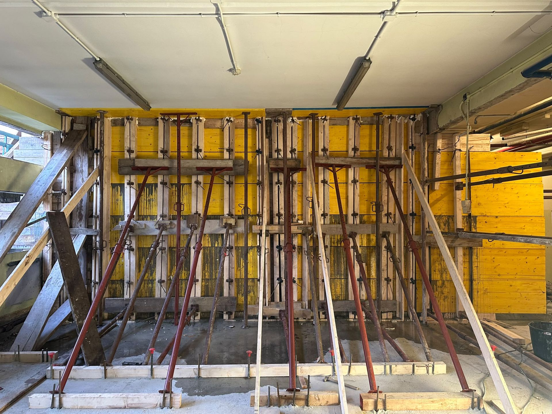 Cantiere con casseforme gialle e numerosi puntelli in acciaio che sostengono una parete