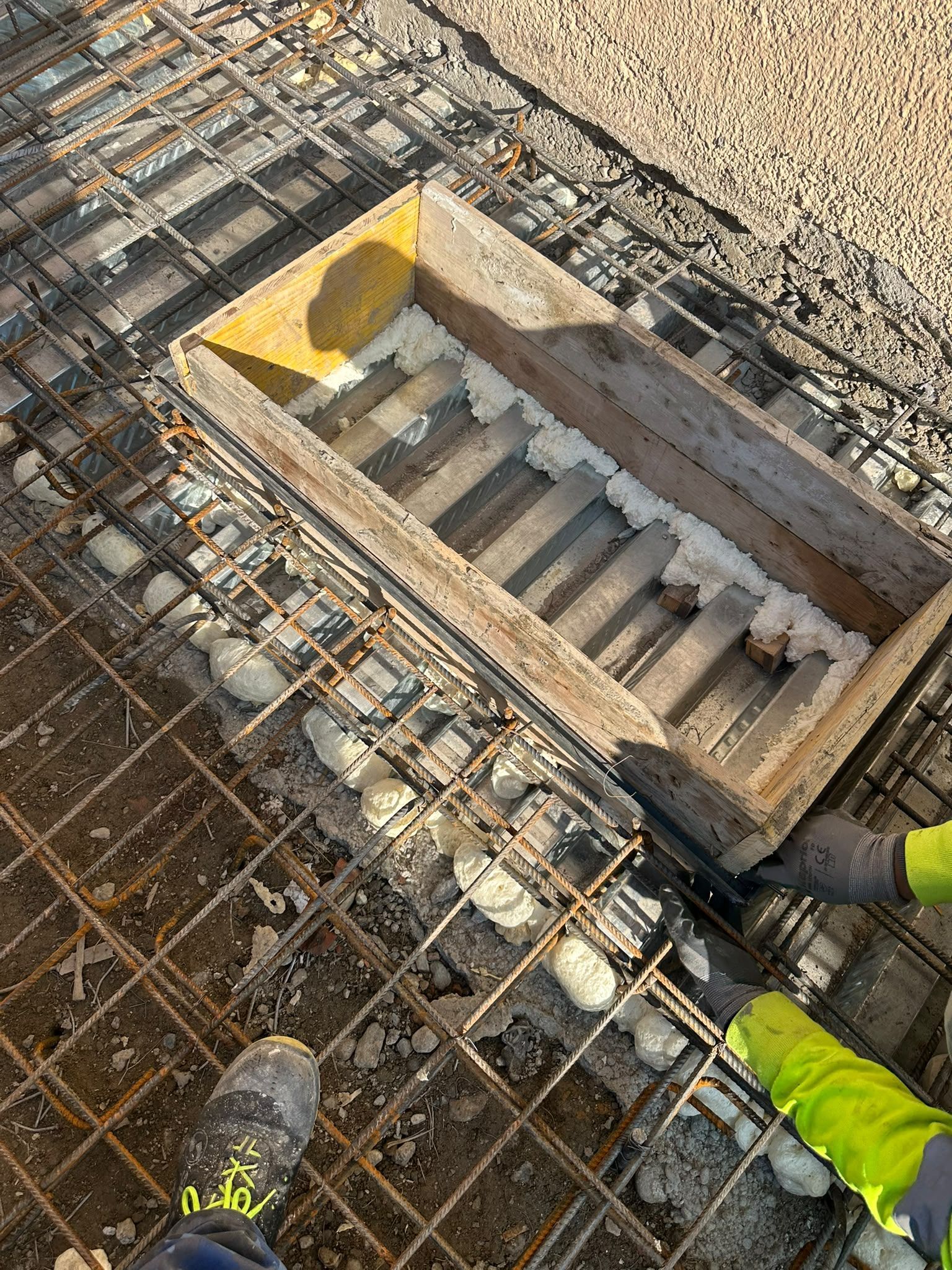 Piano di un cantiere con una griglia di tondini per cemento armato e un’apertura rettangolare per le scale.