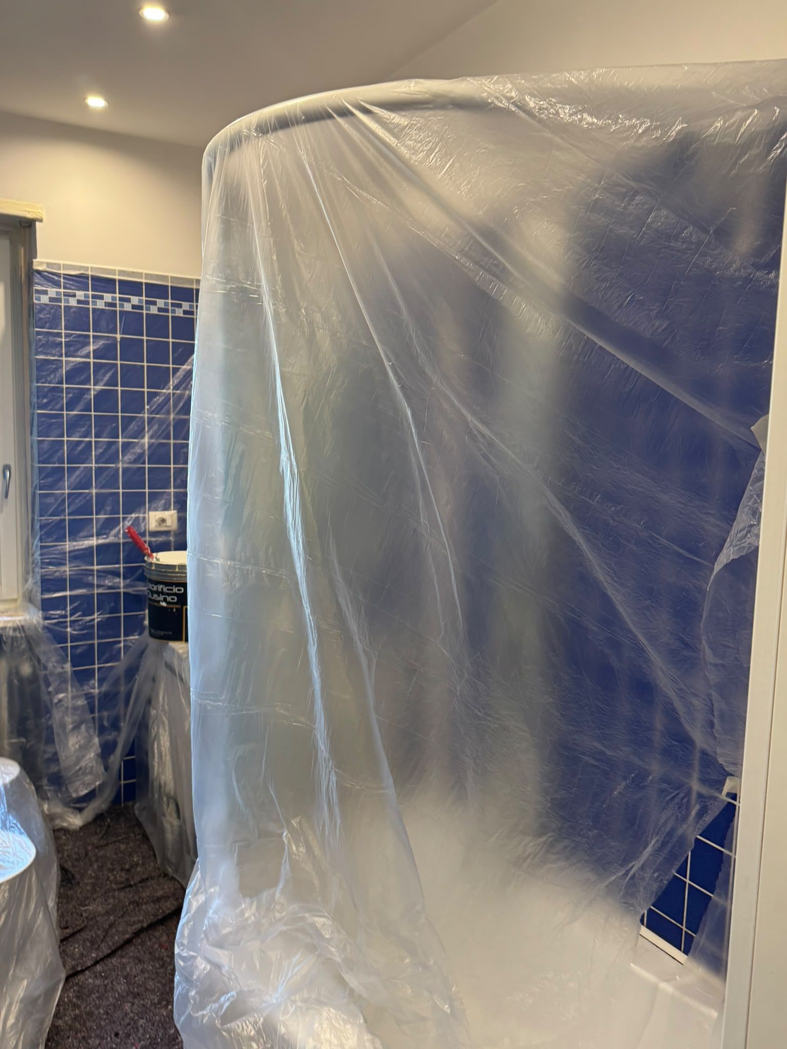 Bagno in ristrutturazione, con una doccia o una vasca avvolta in un telo di plastica trasparente.
