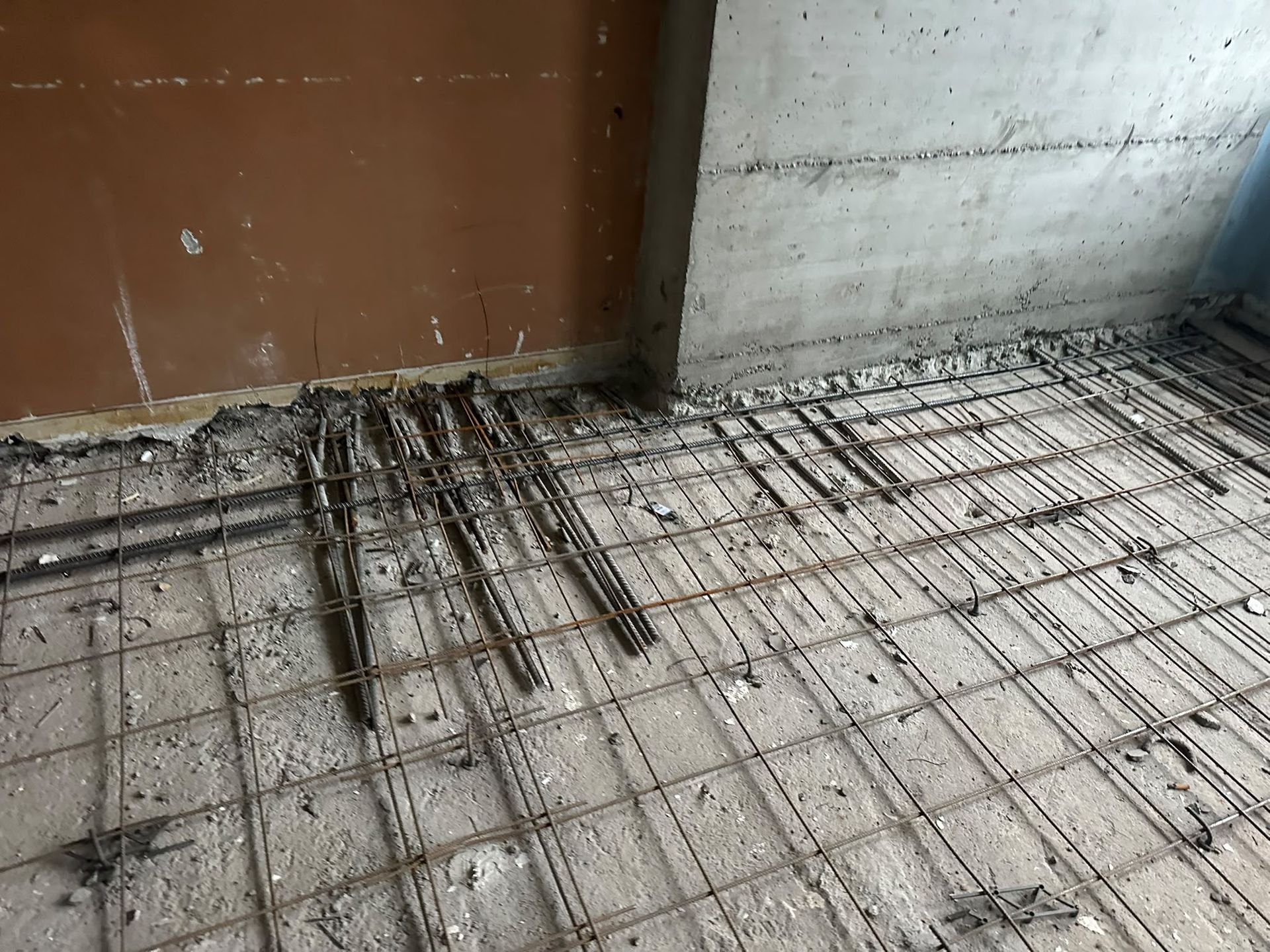 Pavimento in calcestruzzo con rete elettrosaldata vicino a una parete e a un vano porta in costruzione