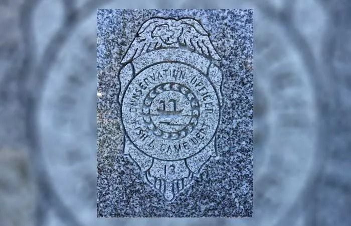 Close-up of a round engraved medal or seal on a speckled gray stone background.