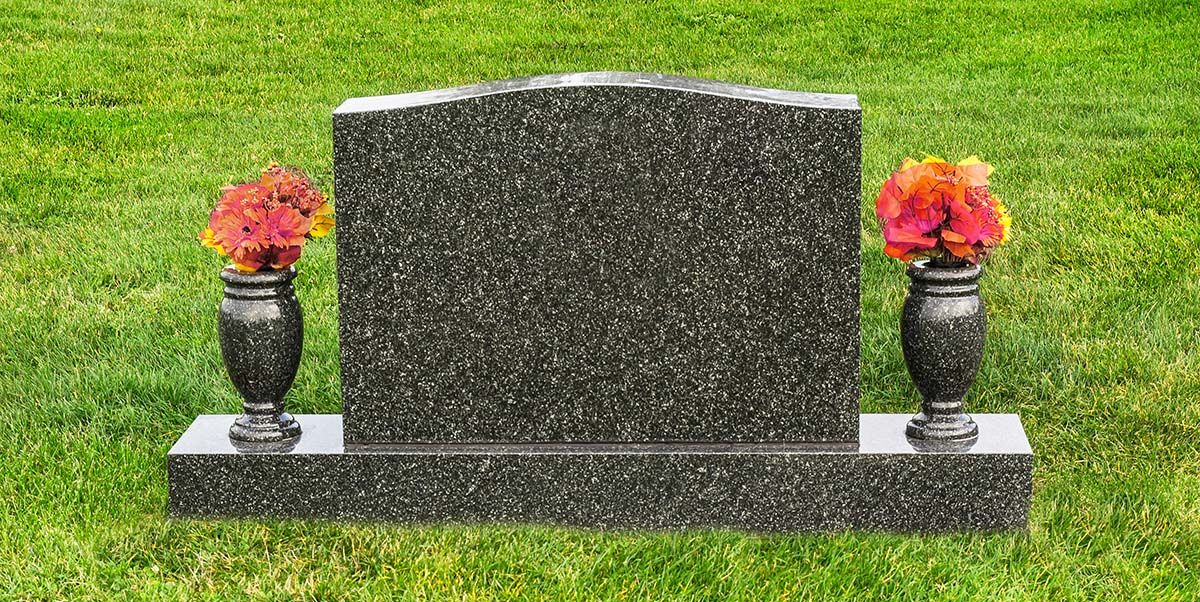 Granite gravestone with two flower vases on a green lawn