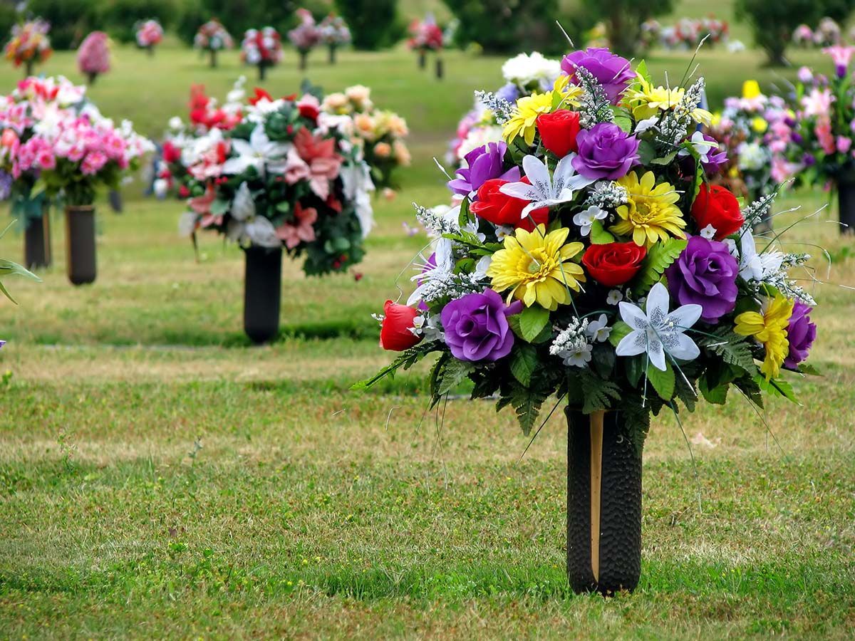 Colorful floral bouquets arranged on black posts in a grassy field