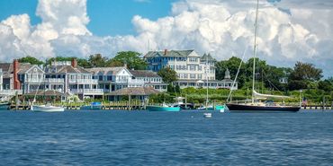 Waterfront resort buildings and sailboats along a blue bay under cloudy skies