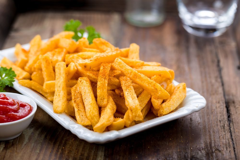 A plate of seasoned French fries with a side of ketchup on a rustic wooden table. — 321 Cafe Learmonth In Learmonth, VIC