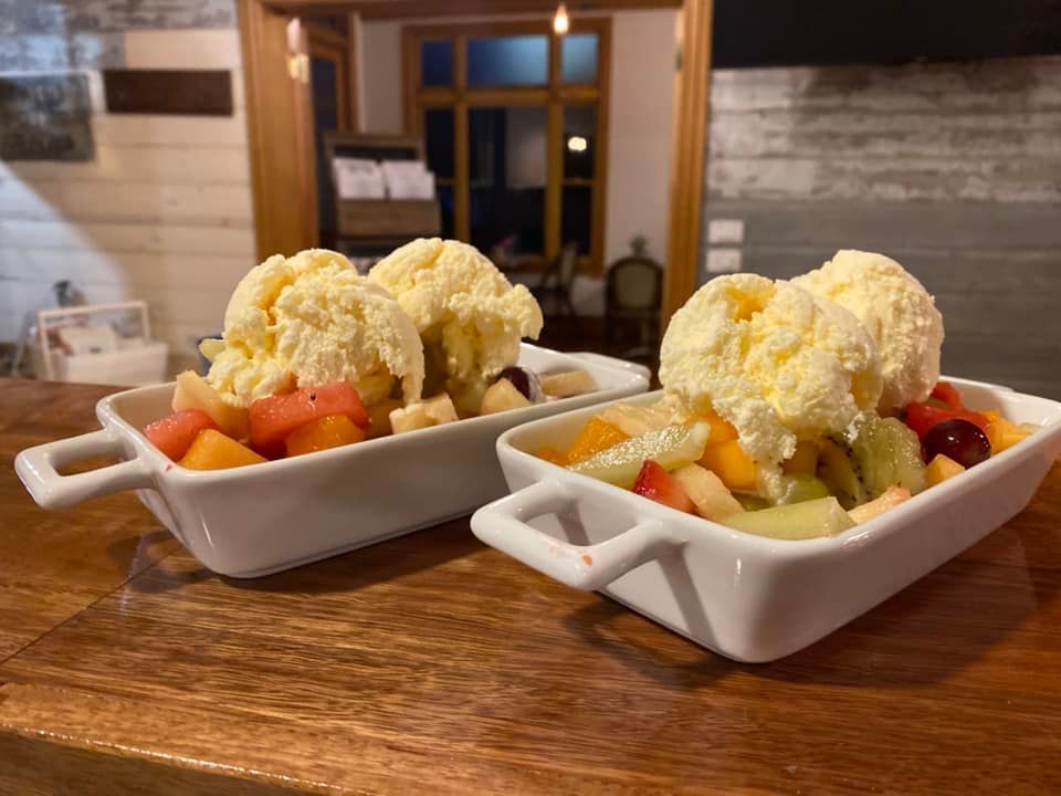 Two Bowls of Fruit Salad Topped With Vanilla Ice Cream on a Wooden Counter — 321 Cafe Learmonth In Learmonth, VIC