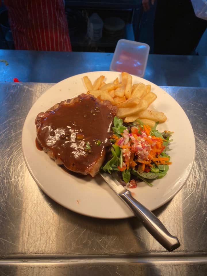 A dinner plate on a metallic surface featuring a steak with gravy, a serving of French fries, and a side salad. — 321 Cafe Learmonth In Learmonth, VIC