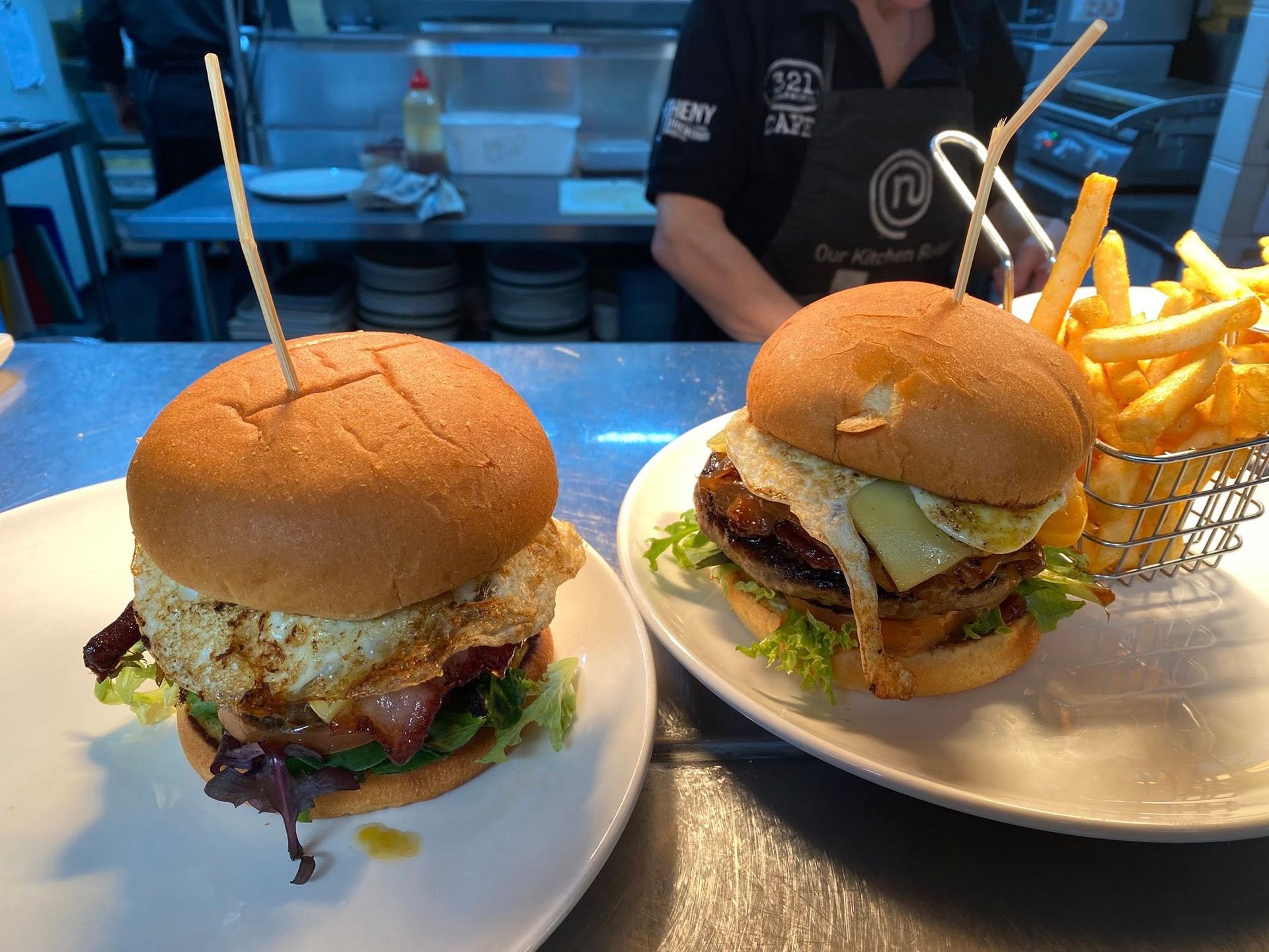 Two Burgers on White Plates, One With a Fried Egg, Alongside a Basket of Fries — 321 Cafe Learmonth In Learmonth, VIC