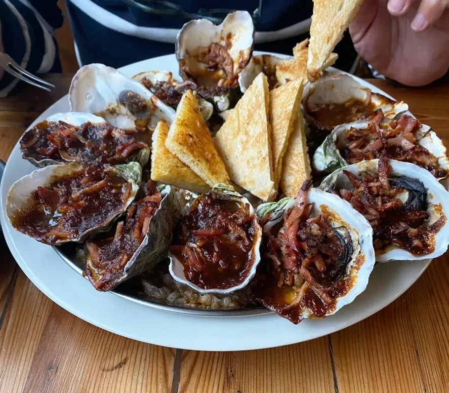 A platter of oysters topped with cooked bacon and sauce, accompanied by triangles of golden toasted bread. — 321 Cafe Learmonth In Learmonth, VIC