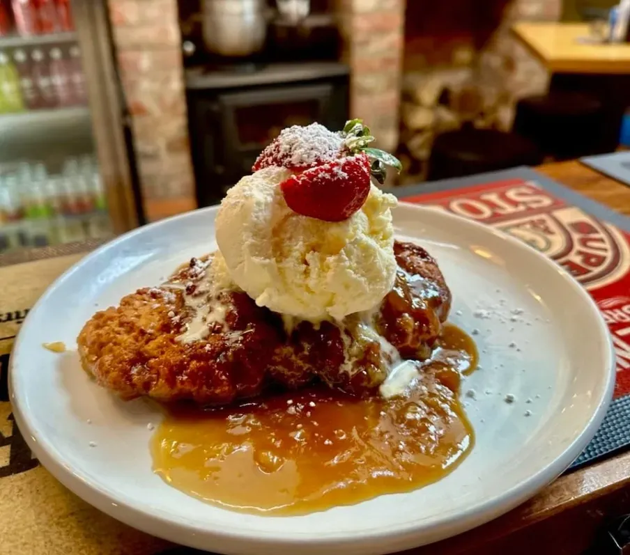 A fried chicken fillet topped with vanilla ice cream and a fresh strawberry, covered in syrup on a white plate. — 321 Cafe Learmonth In Learmonth, VIC