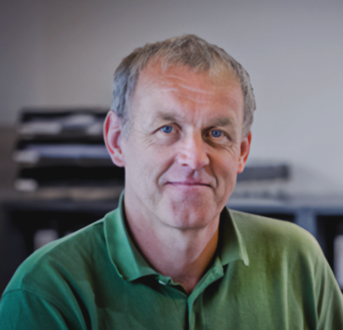 En mand i en grøn skjorte smiler til kameraet