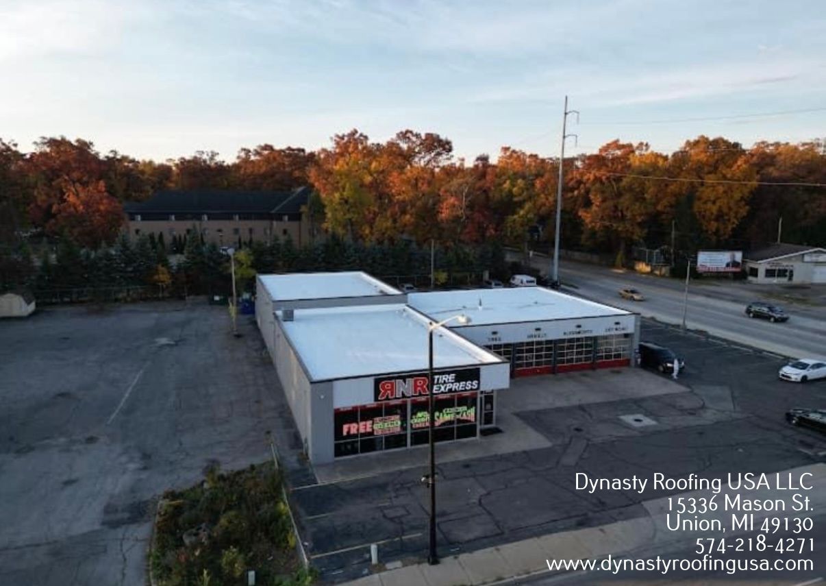 Commercial building with flat roof, surrounded by parking lot and trees; street view.