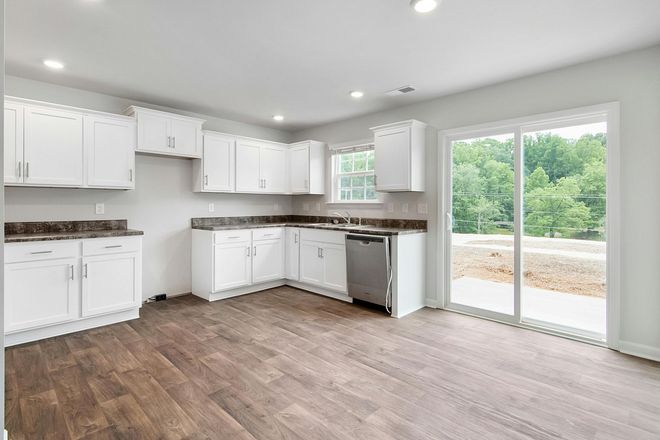 White kitchen with cabinets, stainless steel appliances, and sliding glass door overlooking trees.