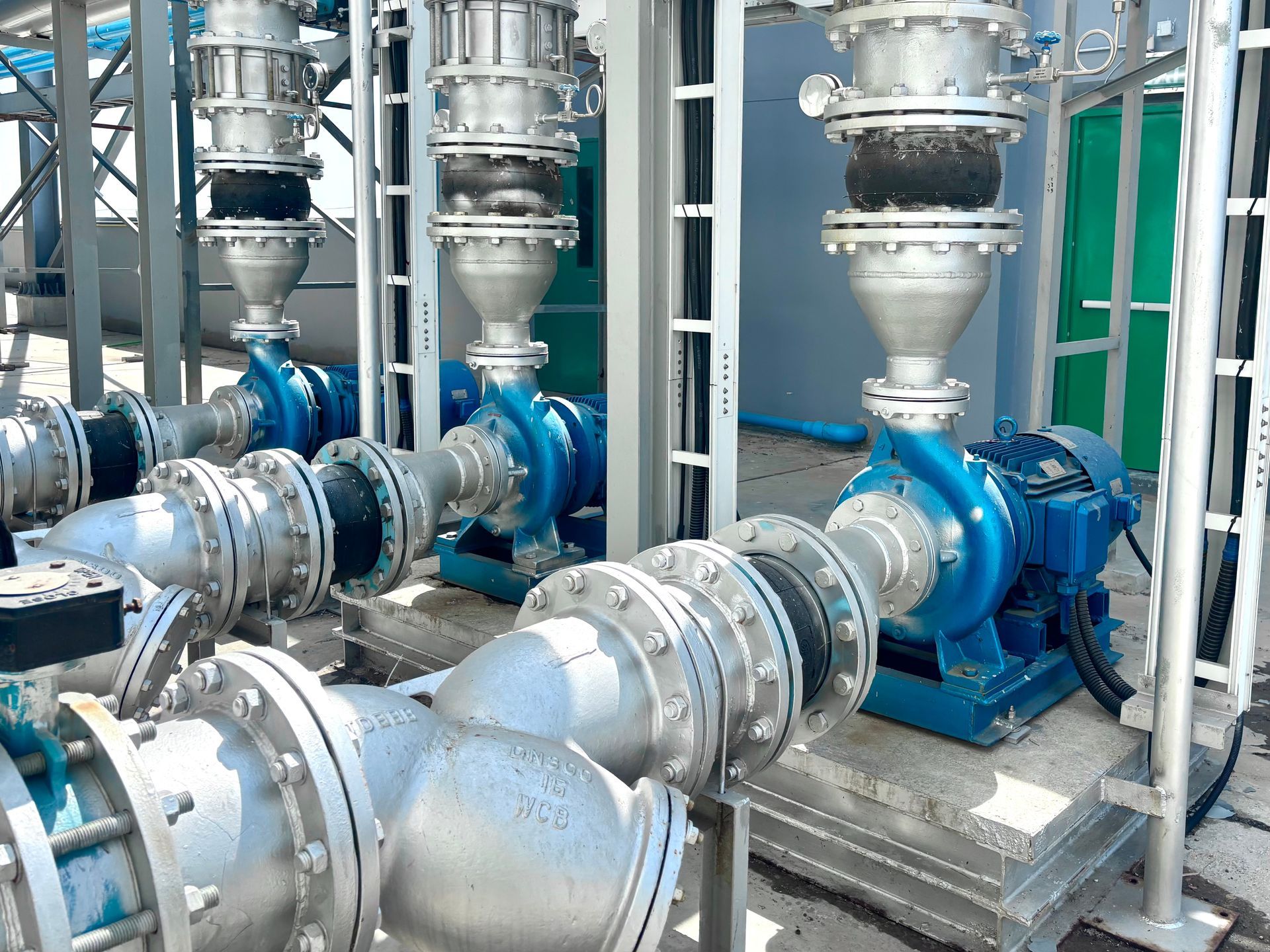 Industrial lift station pumps with steel piping, flanges, and valves outdoors