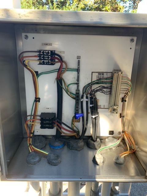 Open electrical control panel with wiring, terminals, and circuit components inside a metal cabinet.