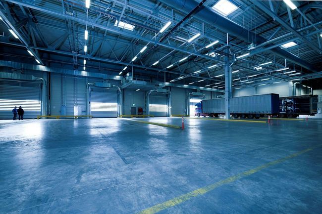 Warehouse interior with large, open space, loading docks, and parked semi-truck trailers.