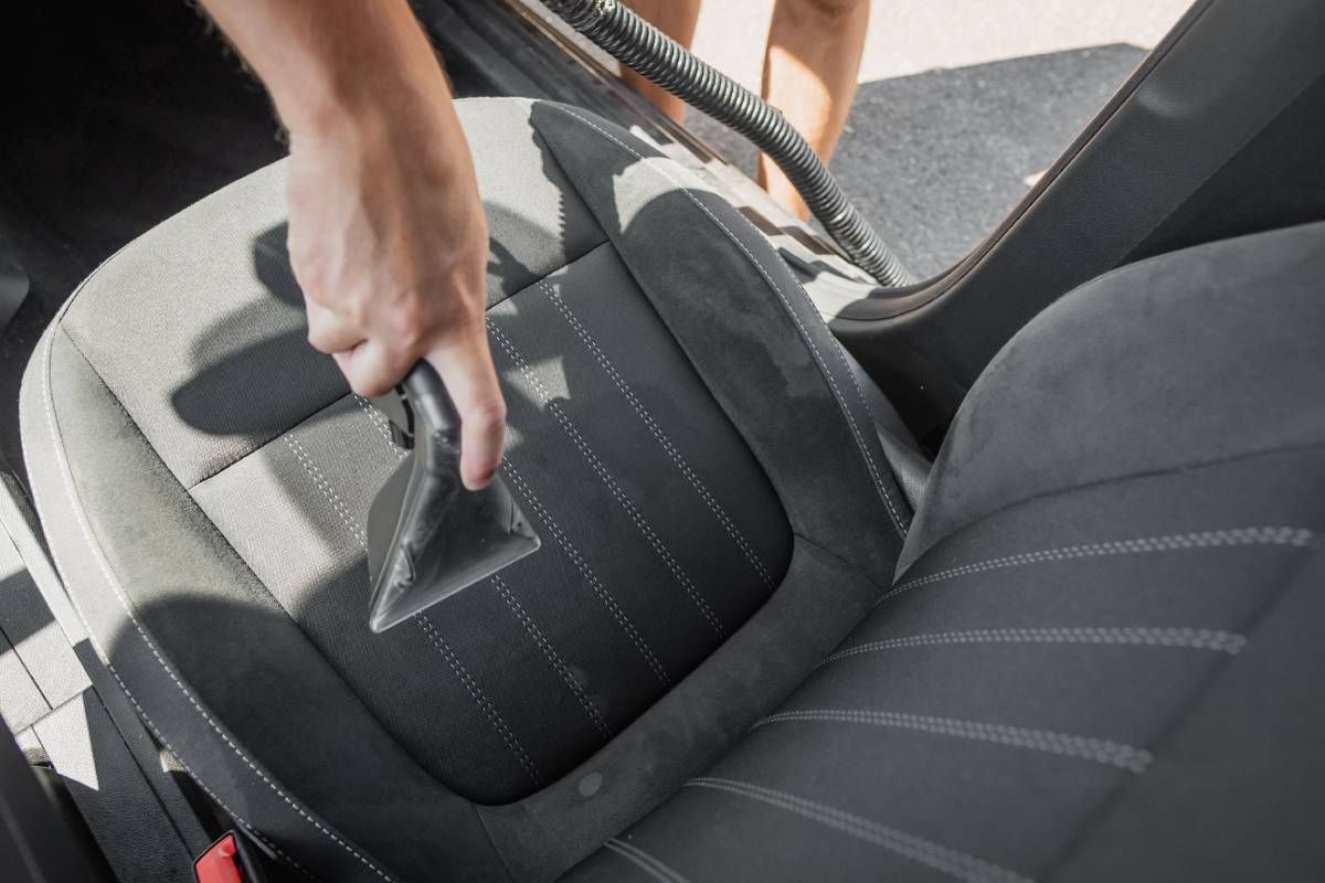 Car detailer vacuuming a seat cushion near Lexington, KY