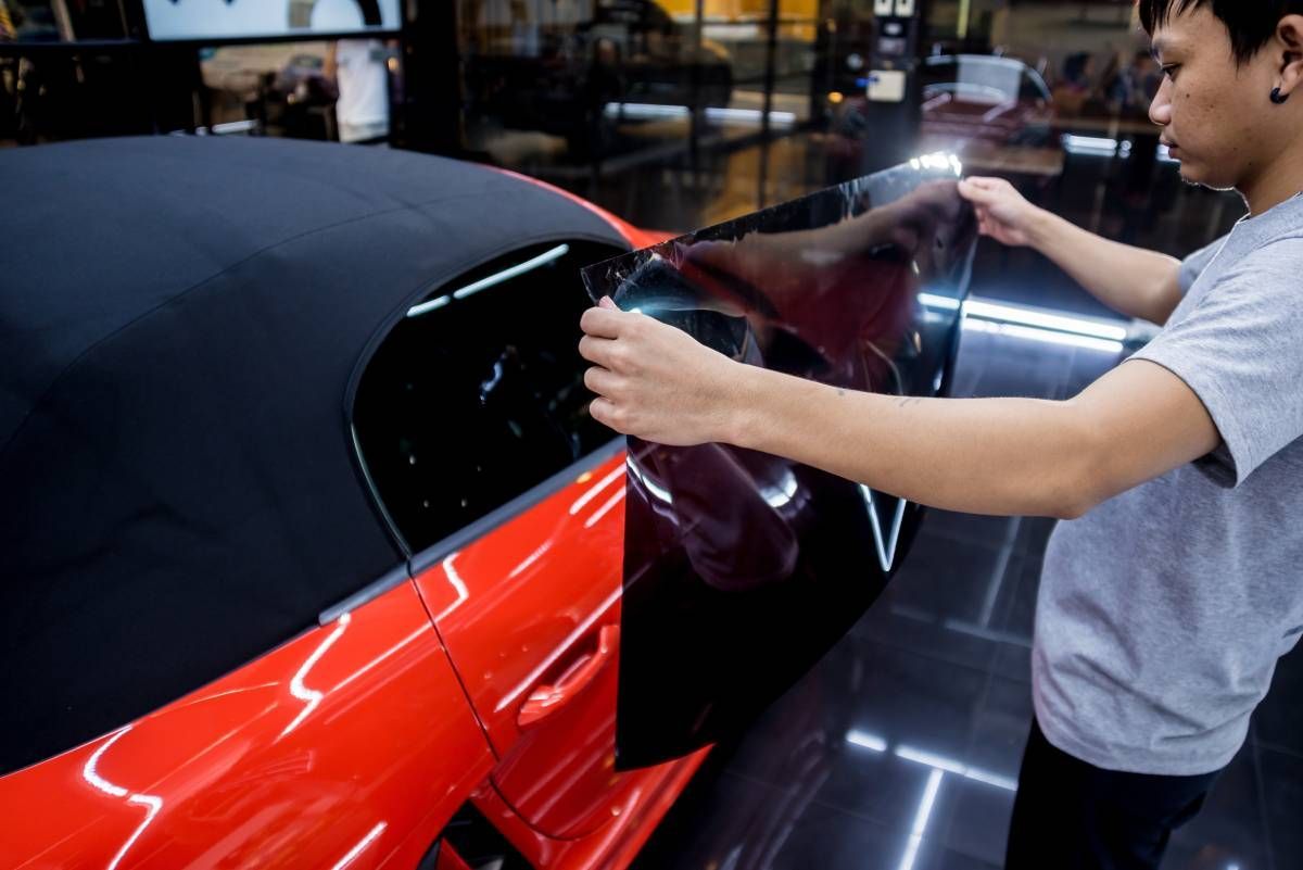 Car service professional applying window tint to a car window