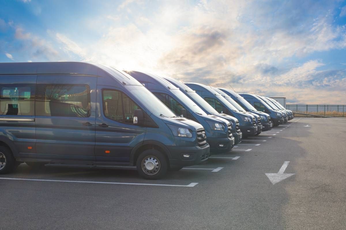 Row of blue commercial vans in a parking lot.