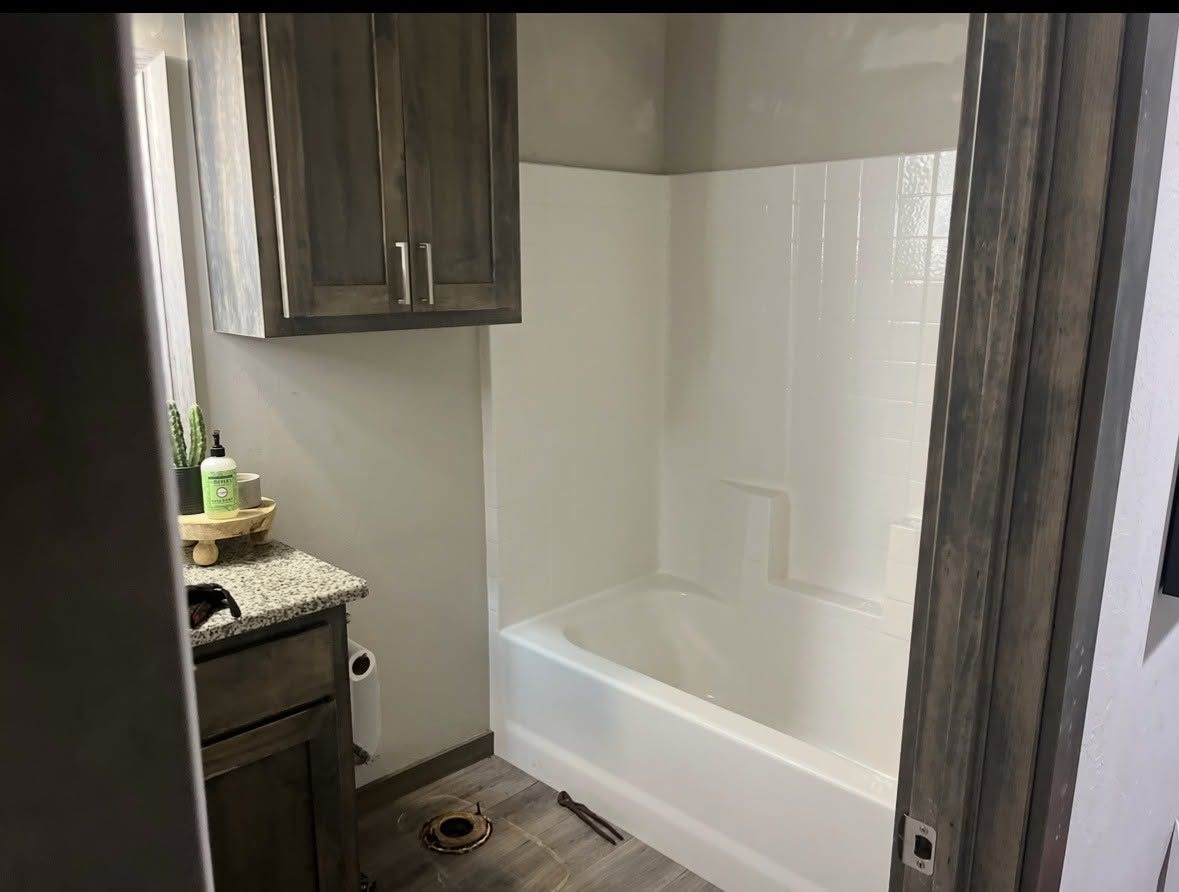 Compact bathroom with dark wood vanity and white bathtub shower surround