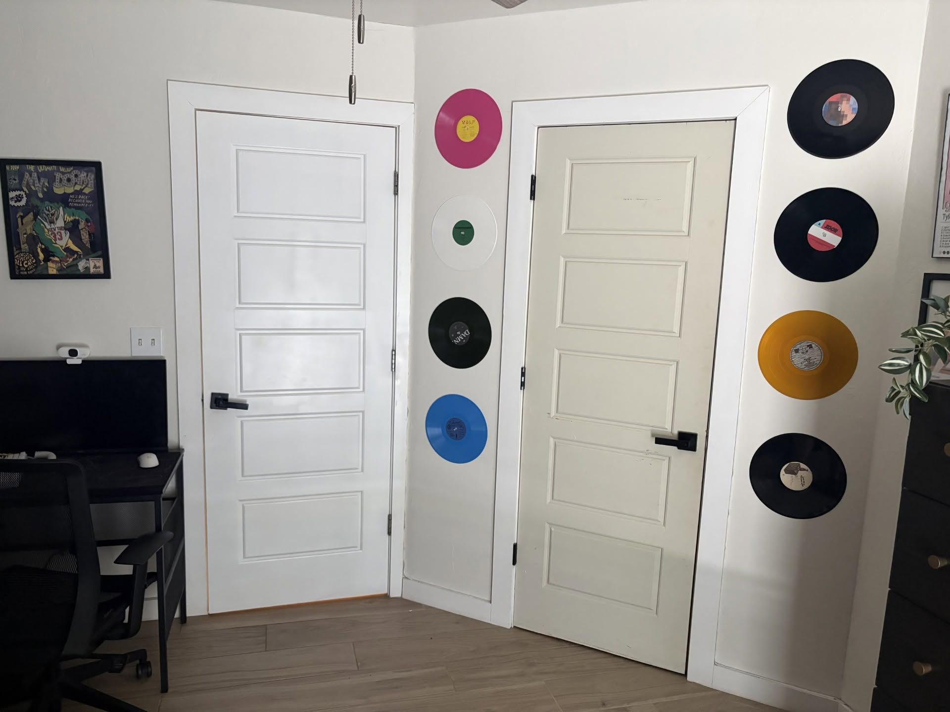 Corner of a room with two white doors and vinyl records mounted on the wall.