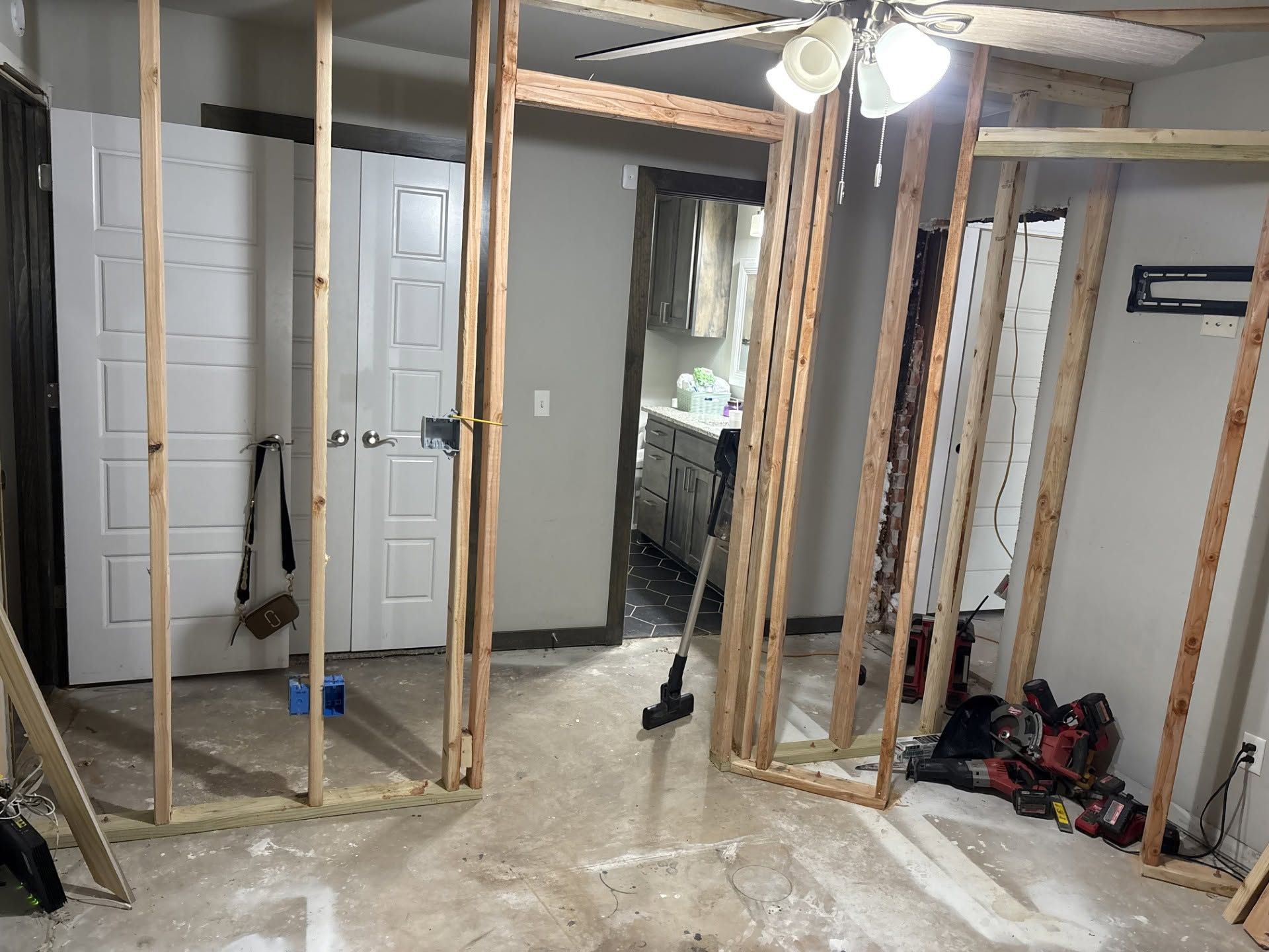 Partially framed interior room with exposed studs, doors, and construction tools on the floor