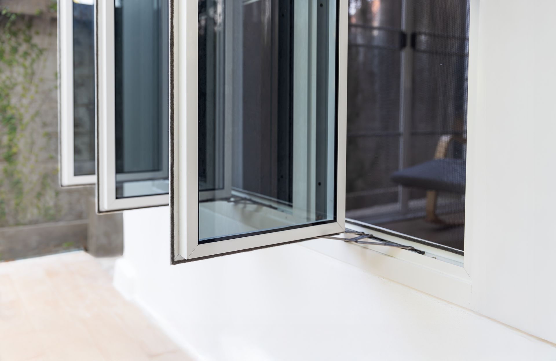 Open glass doors leading to a bright outdoor patio with a white floor and gray walls