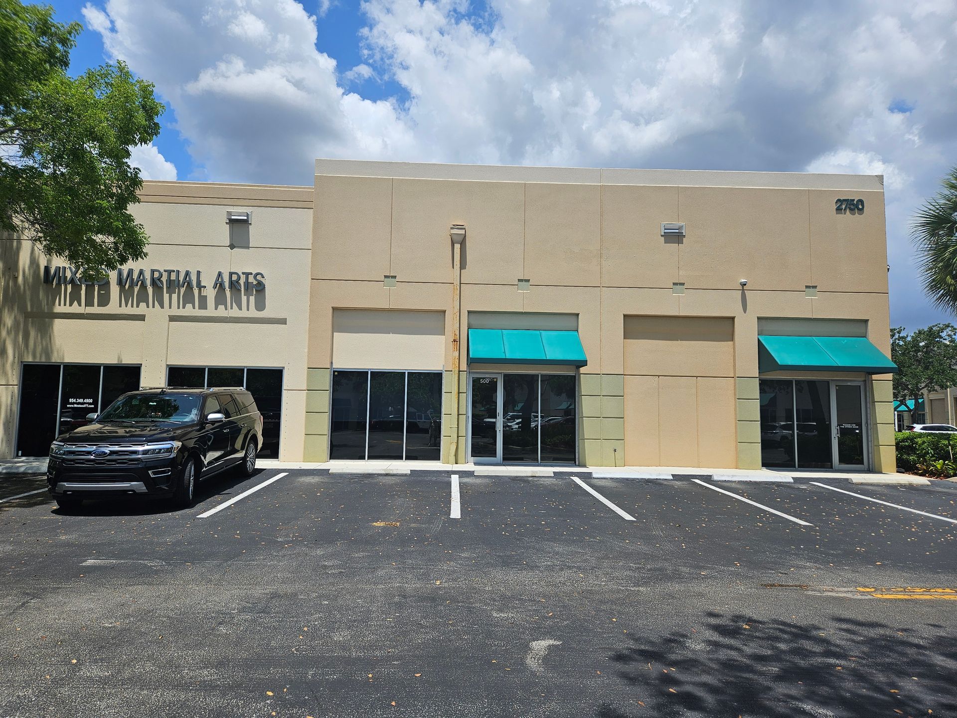 A car is parked in front of a building that says martial arts