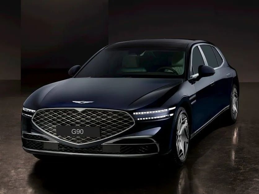 A dark blue Genesis G90 luxury sedan parked against a dark, minimalist background.