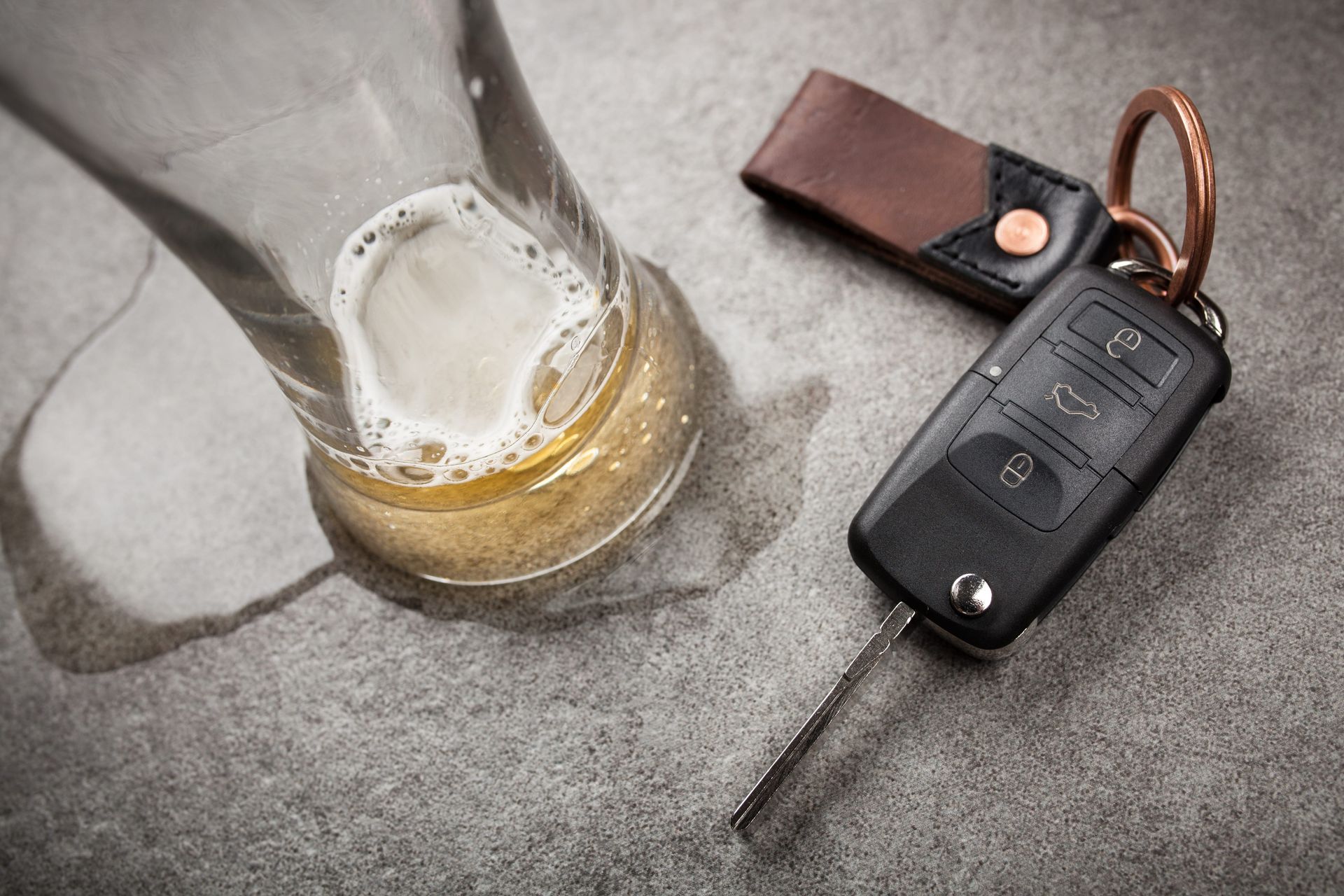 Beer glass and car key fob on a gray bar counter