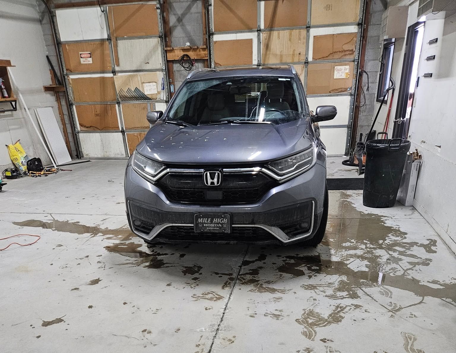 Silver Honda SUV parked inside a garage with wet floor and closed wooden doors behind it