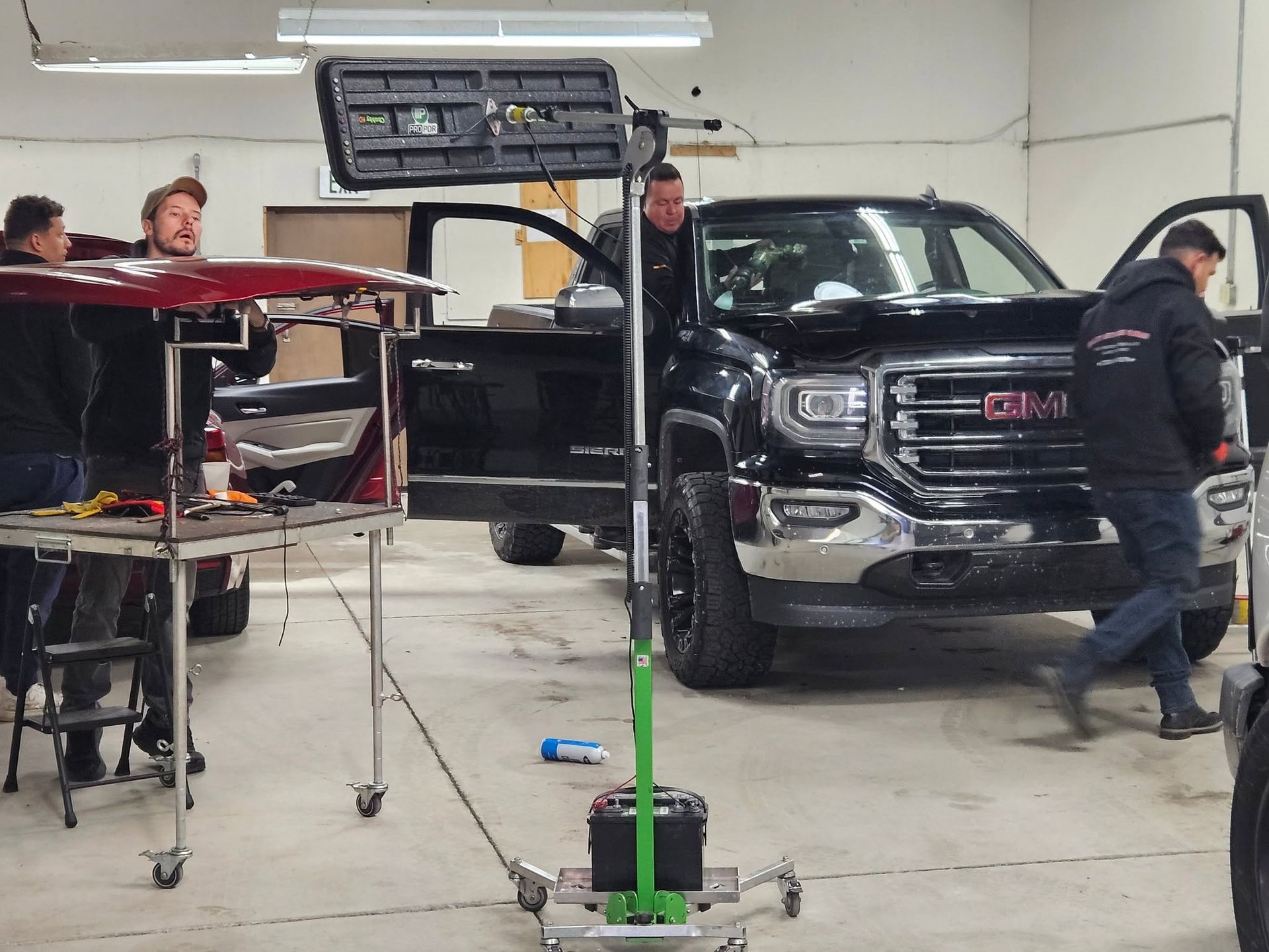 Black GMC truck in a garage with mechanics working around it on lifts and tools.