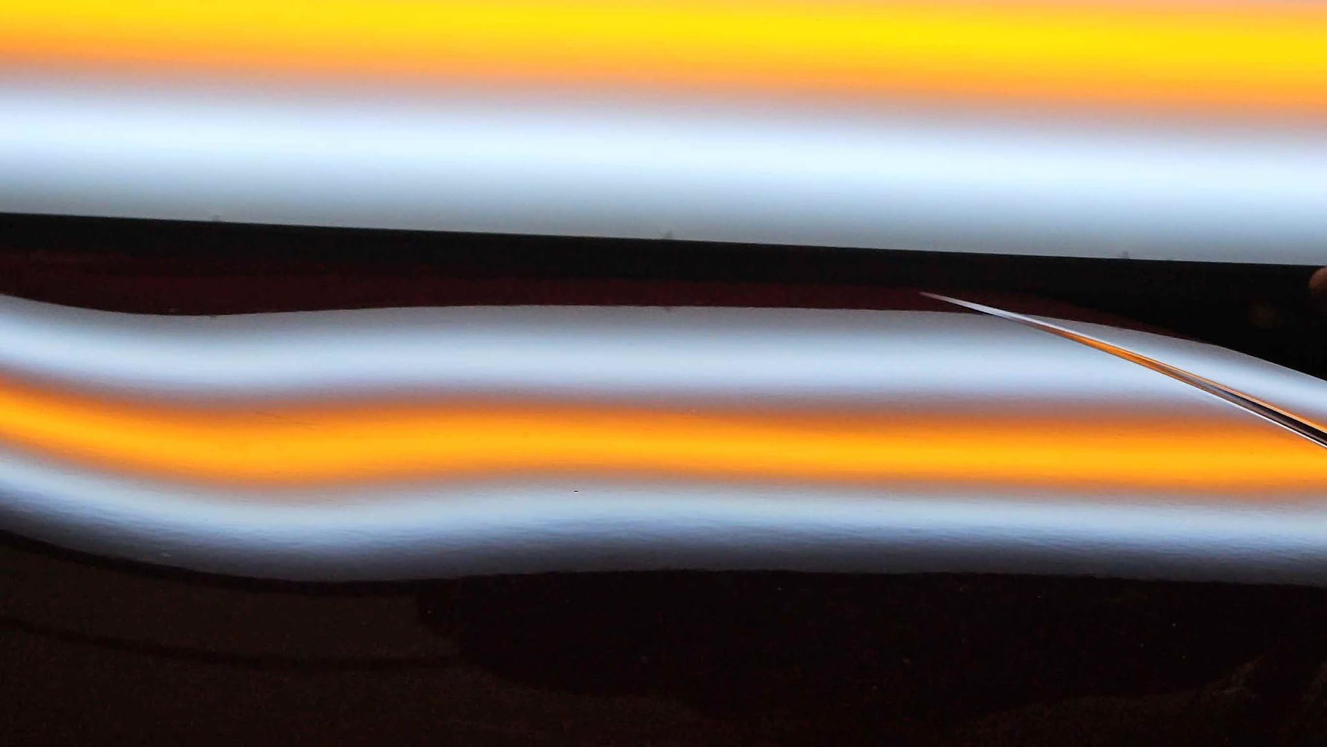 Abstract close-up of glossy black, white, and orange horizontal streaks