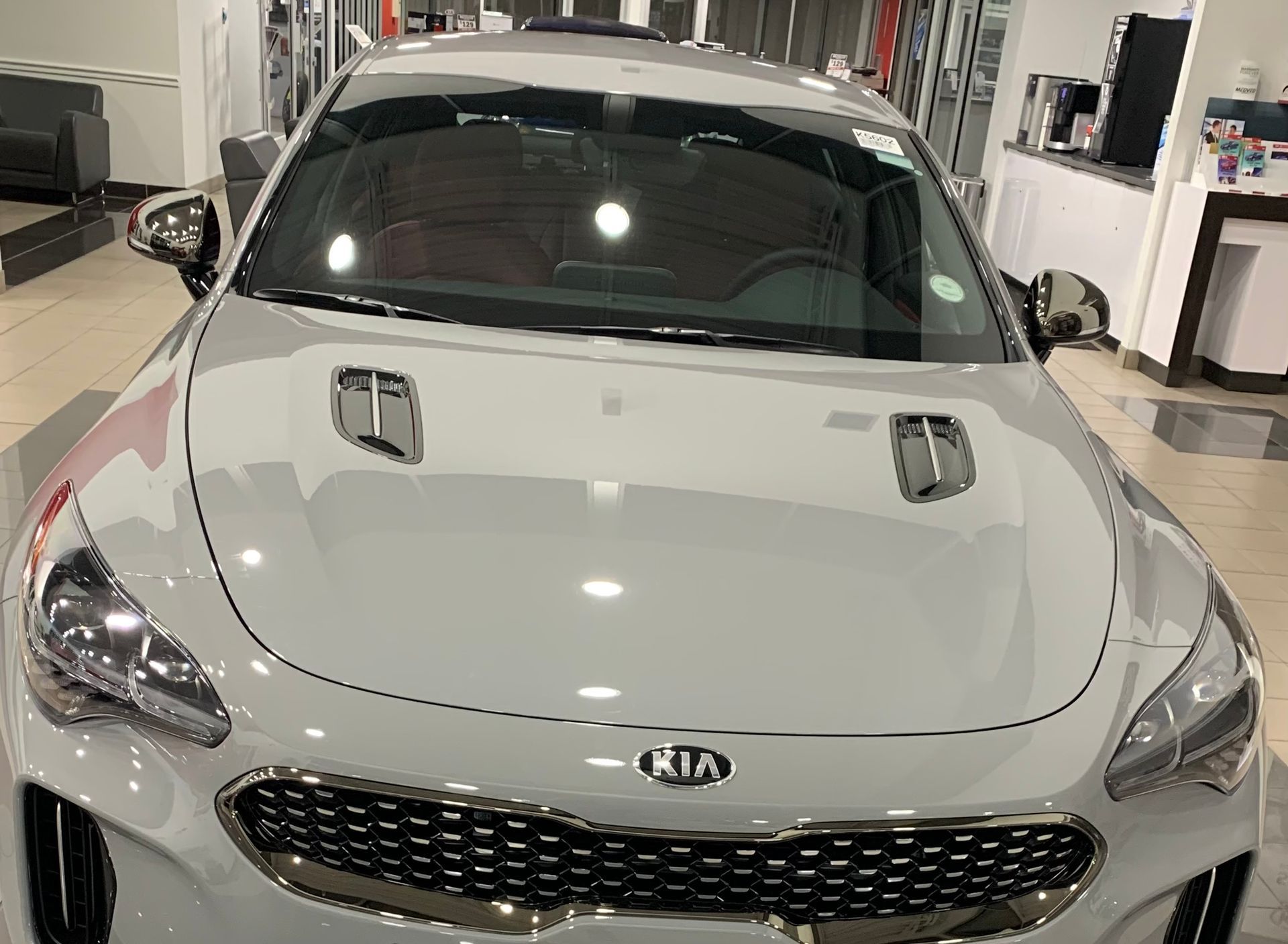 Front view of a silver Kia parked indoors in a showroom or service area.