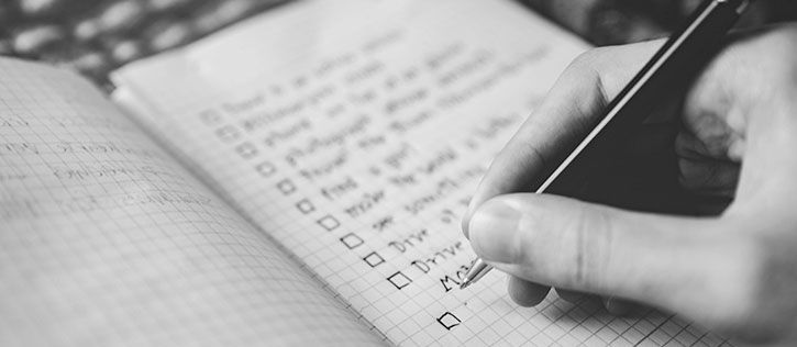 Black and white picture of someone writing a list to preplan.