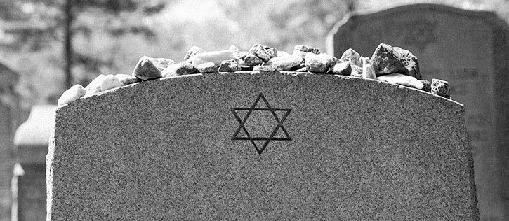 Jewish gravestone engraved with a Star of David, with memorial stones left by mourners.