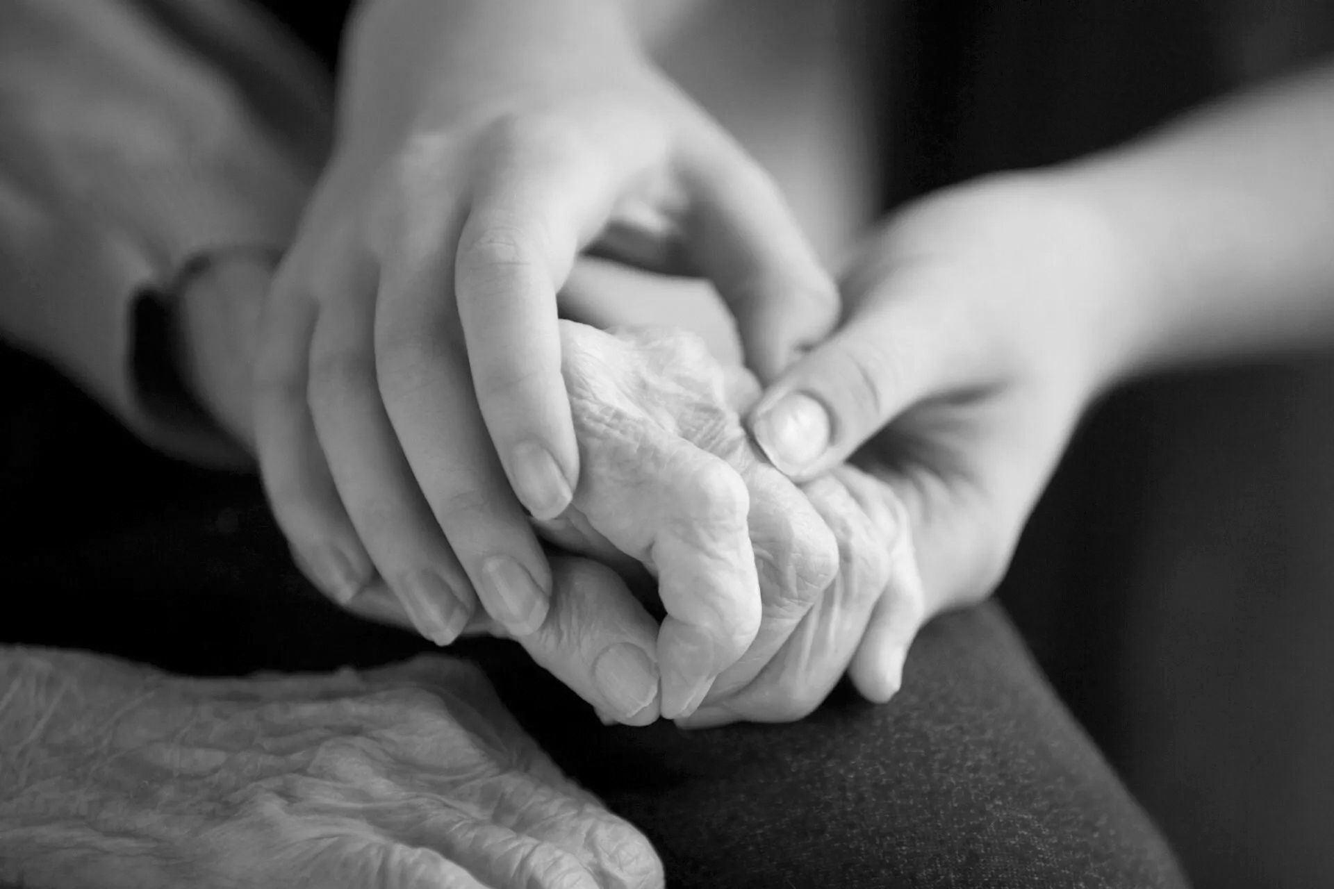 An elderly hand clasped in a young loved one's, reflecting the need for guidance into the next phase after death.