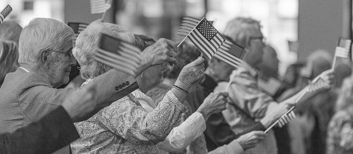 A group of men and women carrying small flags, assembled to honor veterans on Memorial Day