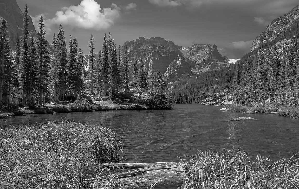 Peaceful Colorado mountain lake surrounded by pine forests and peaks, representing a meaningful location for scattering ashes after cremation services in Colorado.