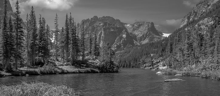 Peaceful Colorado mountain lake surrounded by pine forests and peaks, representing a meaningful location for scattering ashes after cremation services in Colorado.