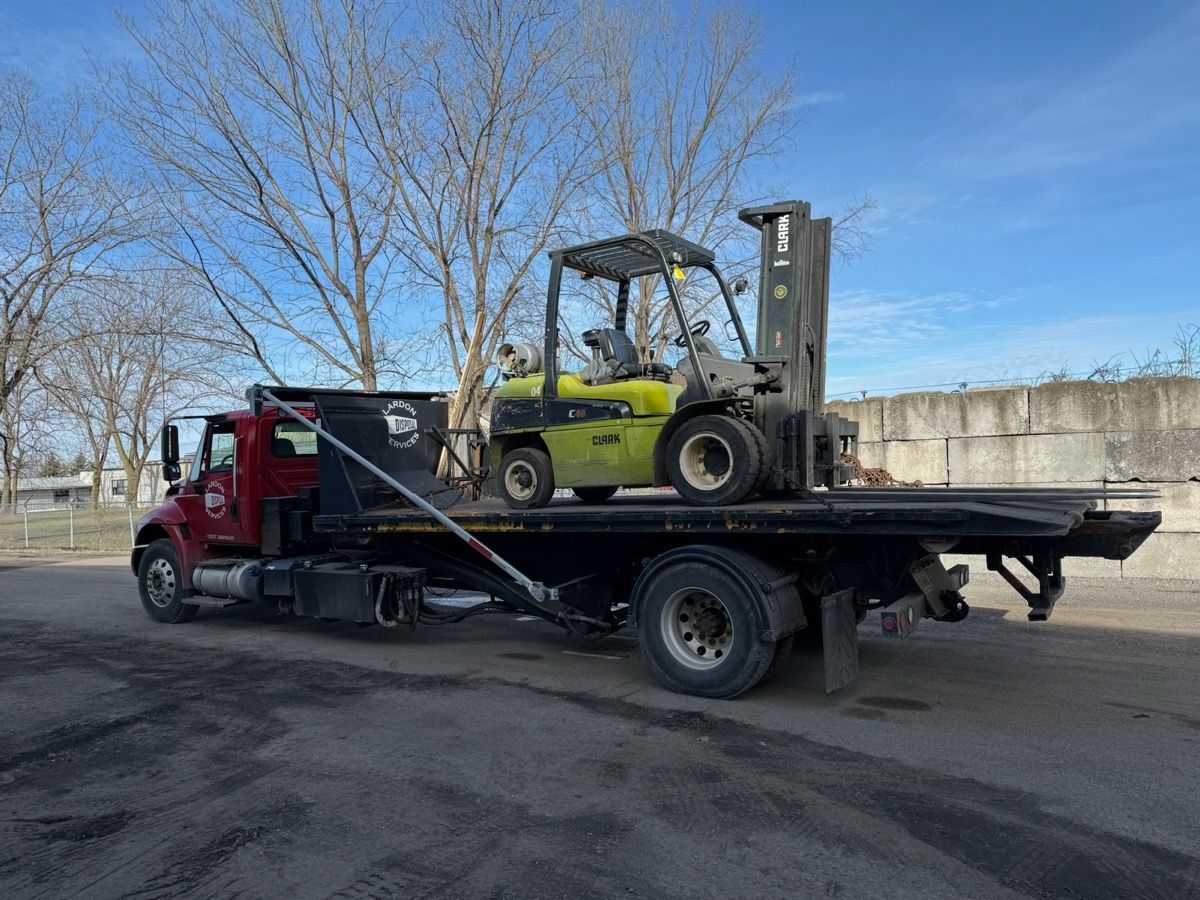A red dump truck is parked in a gravel lot next to a solar panel.