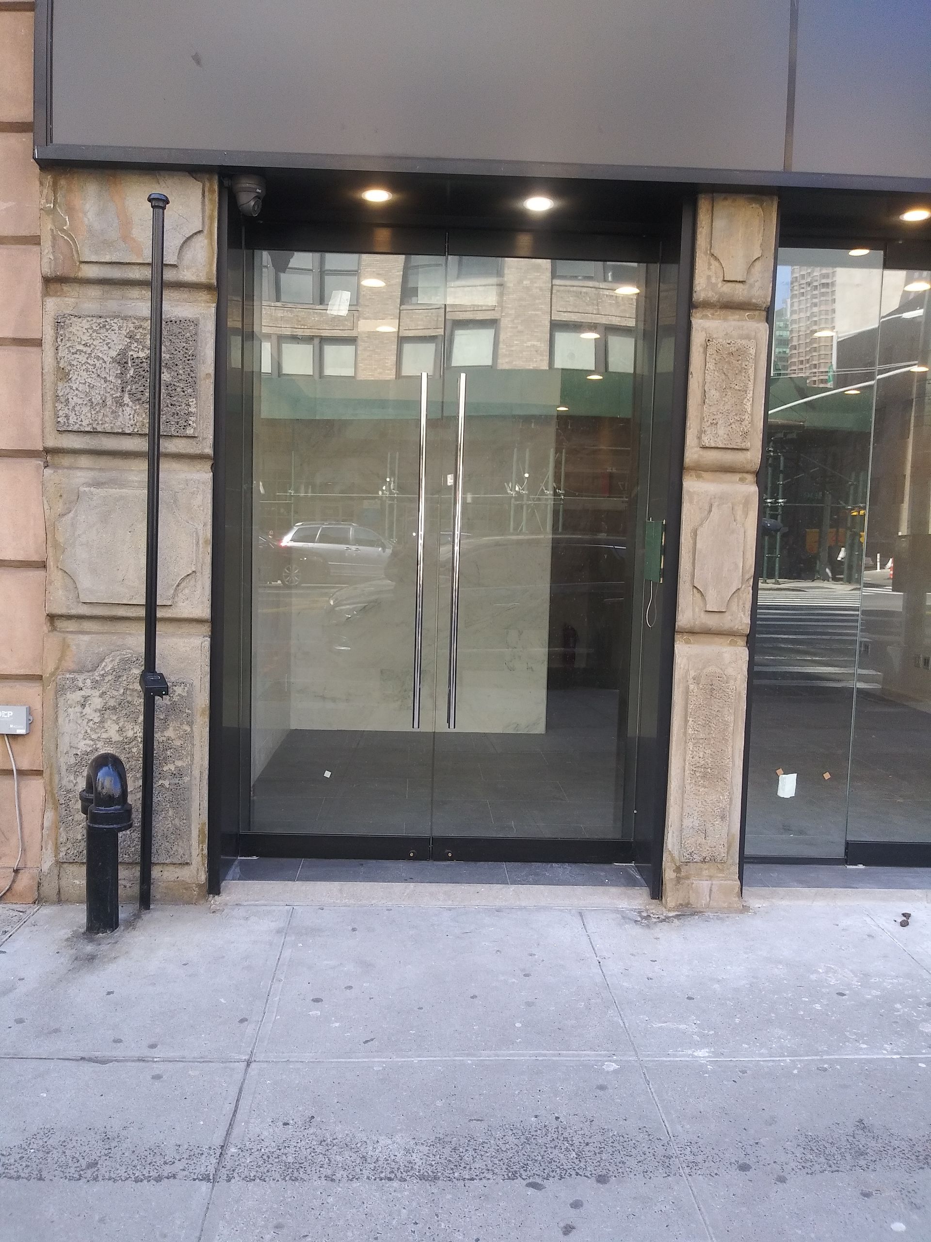 Glass storefront entrance with stone columns and sidewalk in front